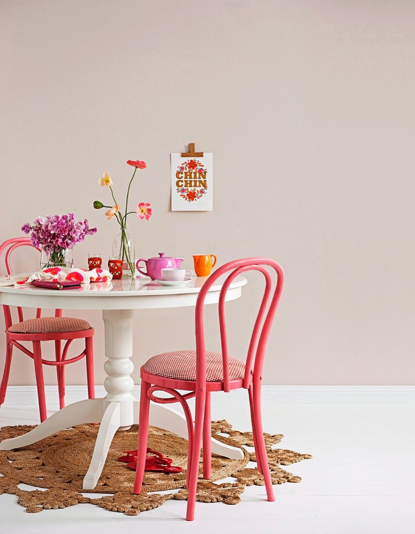 In Pink lackierte, klassische Bugholzstühle und weisser Landhaustisch auf Strohteppich