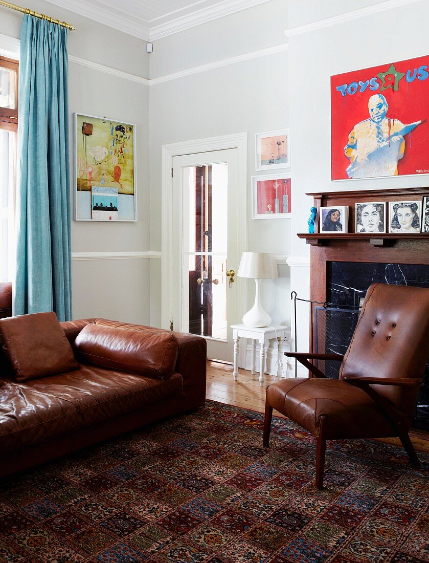 Brown leather sofa and armchair in front of fireplace in corner of traditional living room