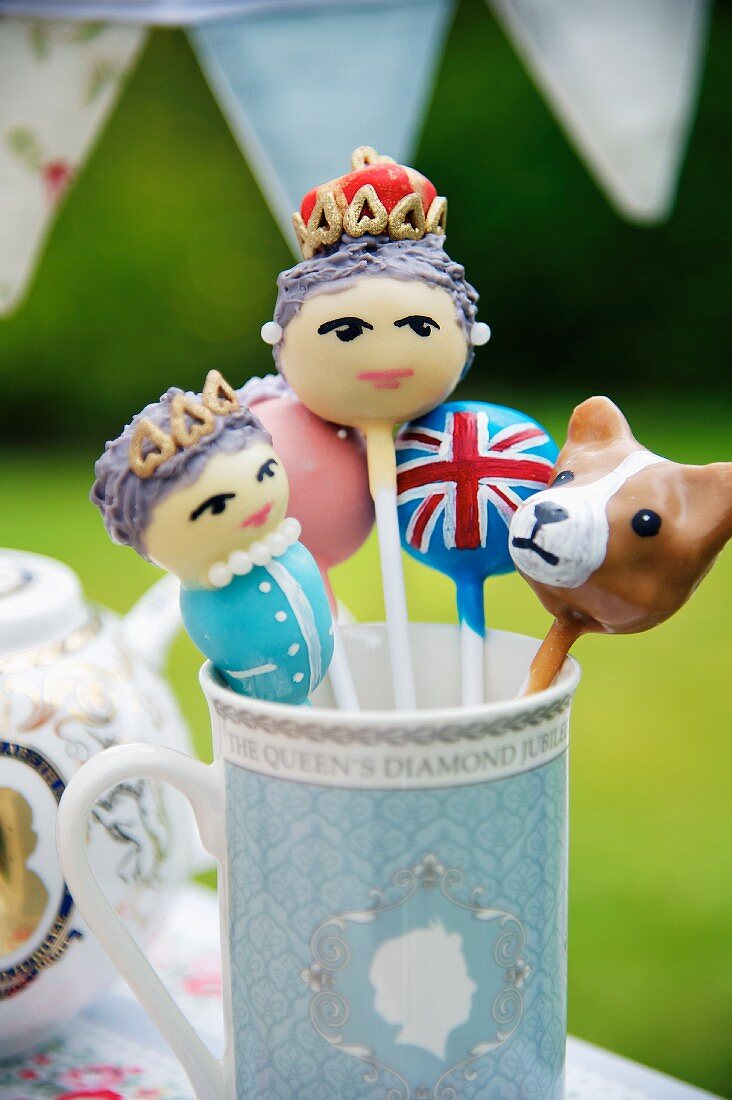 Nahaufnahme witziger Motiv-Lollies mit stilisierten Köpfen der Queen, Union Jack und Hundekopf in englischem Teebecher