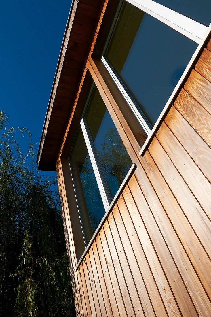 Holzfront eines zeitgenössischen Holzhauses mit großen Glasfenstern