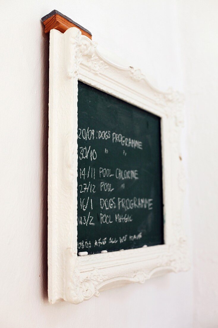 Notes on wall-mounted chalkboard with white, ornate frame