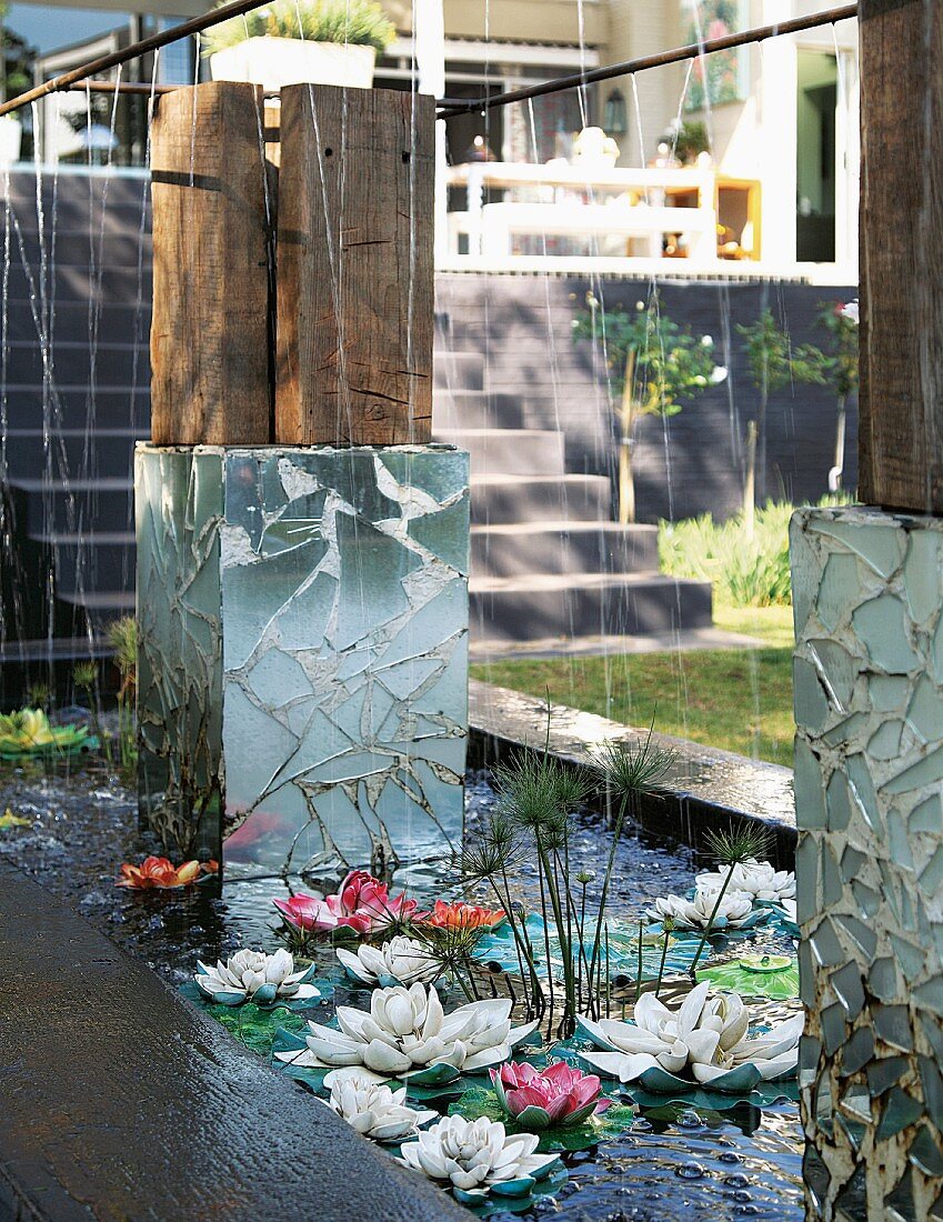 Künstliche Seerosen und Kunstobjekte im Wasserbassin unterhalb eines Wohnhauses