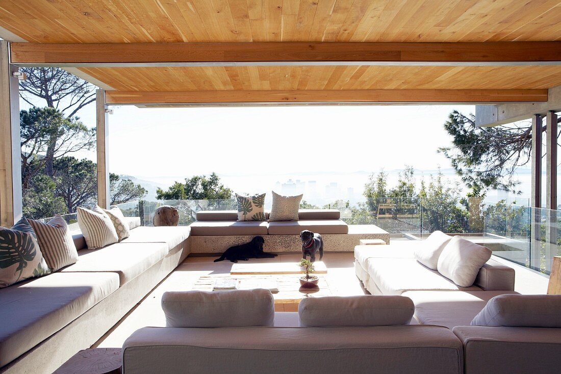 Sofa combination in terrace-style living room; smooth wooden ceiling supported on steel girders