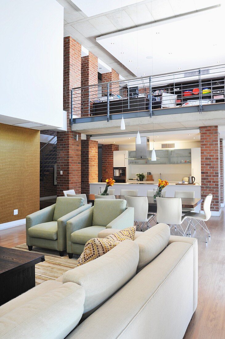 Open-plan living-dining area in architect-designed house with brick wall and mezzanine
