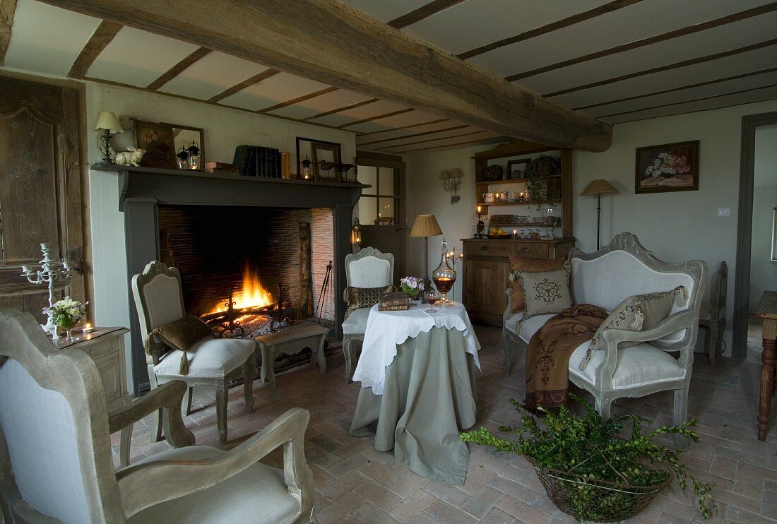 Cosy room with fireplace, low beamed ceiling and brick floor; vintage seating in front of open fire