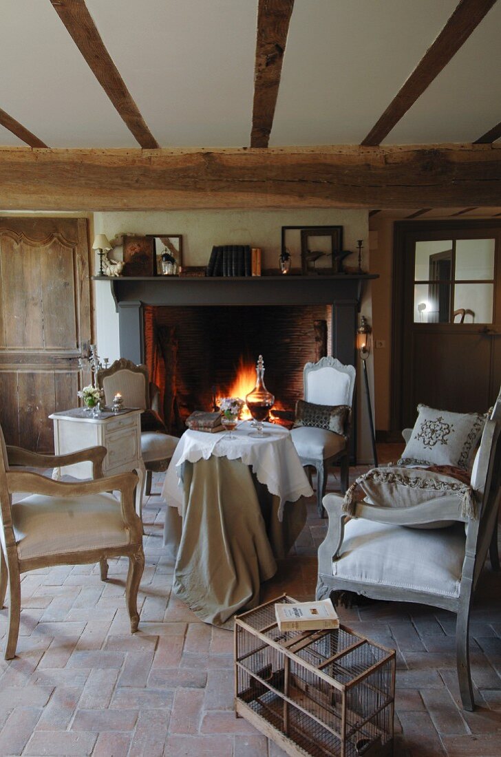 Nostalgic seating area in natural shades with large open fire; old bird cage in foreground