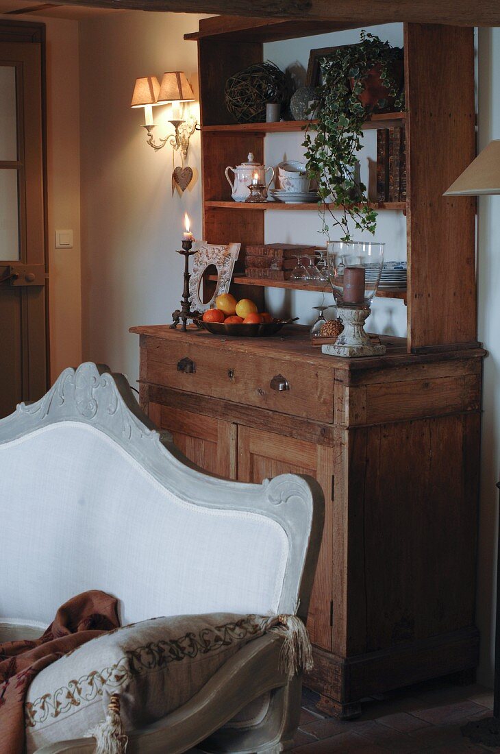 Wooden dining room dresser with simple top unit; antique sofa in natural shades in foreground