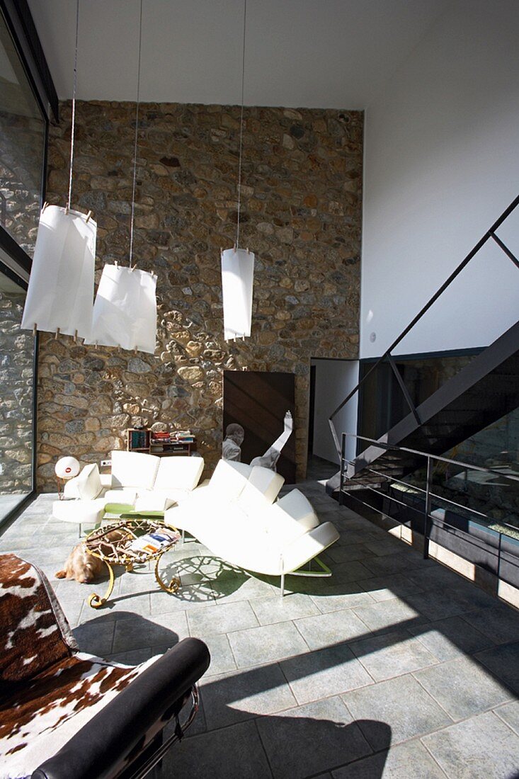 Modernes, sonniges Wohnzimmer mit Natursteinwand und originellen Möbeln