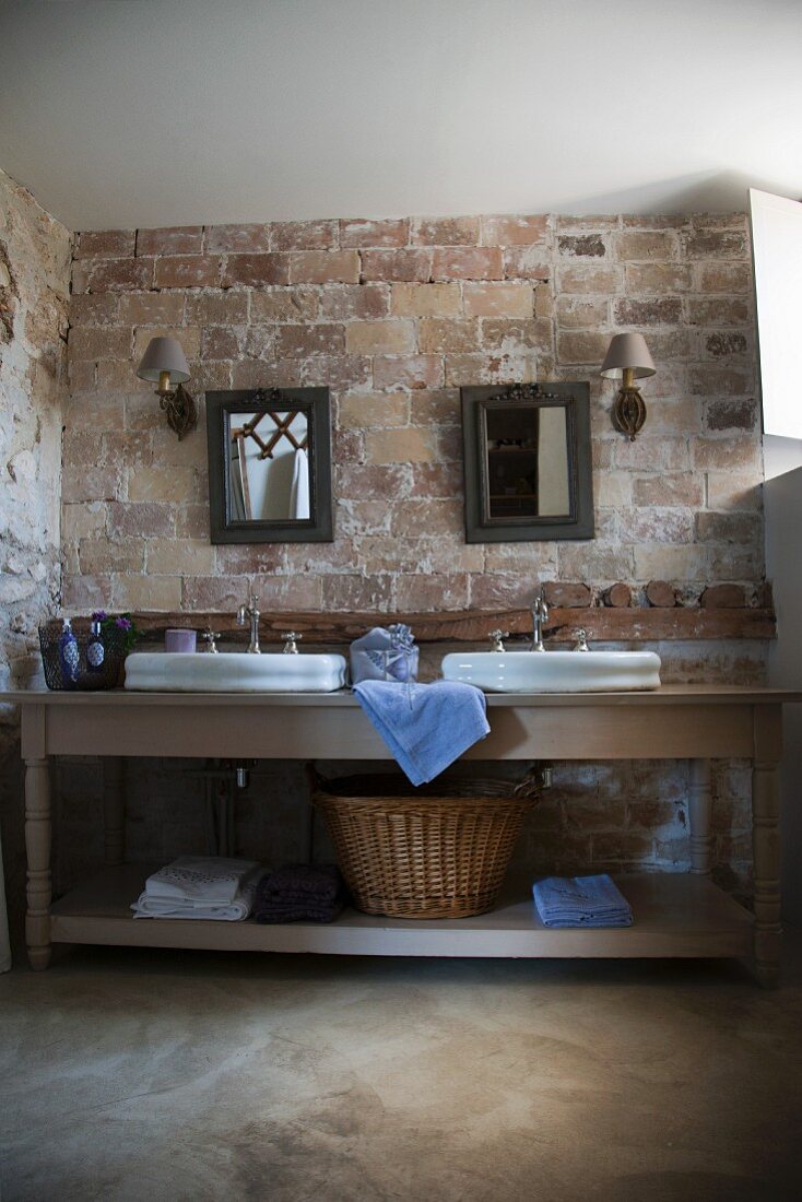 Waschtisch mit zwei Becken vor rustikaler Ziegelwand im Badezimmer eines provenzalischen Landhauses