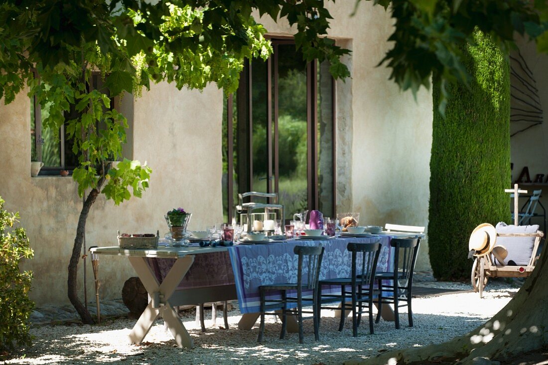 Rustic wooden table and simple wooden chairs outside Provençal country house
