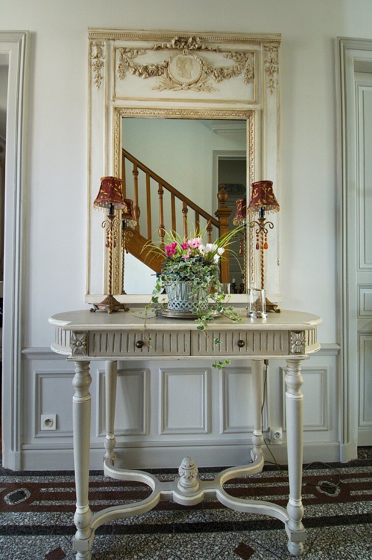 Grauer Wandtisch mit gerahmtem Wandspiegel und sich spiegelndem Treppenaufgang