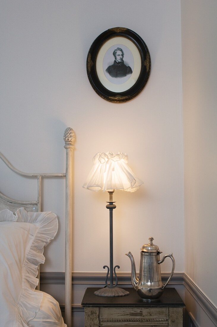 Ovales Portrait über nostalgischer Nachttischlampe und silberner Kaffeekanne auf Nachttisch