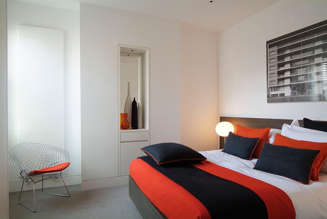 Orange schwarz gestreifte Tagesdecke auf Bett und Klassiker Stuhl in modernem Schlafzimmer
