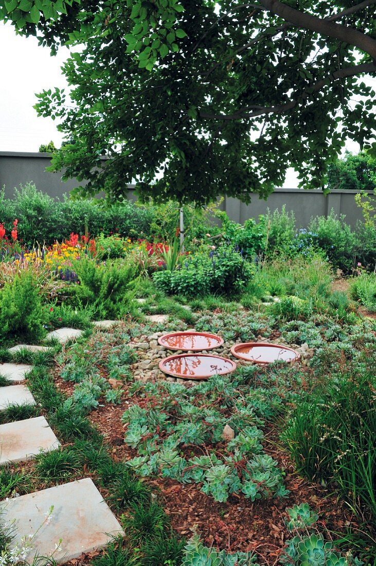 Garten mit Weg aus Steinplatten & Wasserschalen als Deko