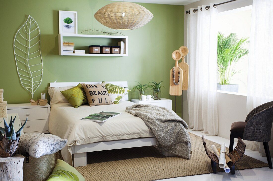Modernes, helles Schlafzimmer mit pastellgrüner Wand, weissen Möbeln und Sisalteppich