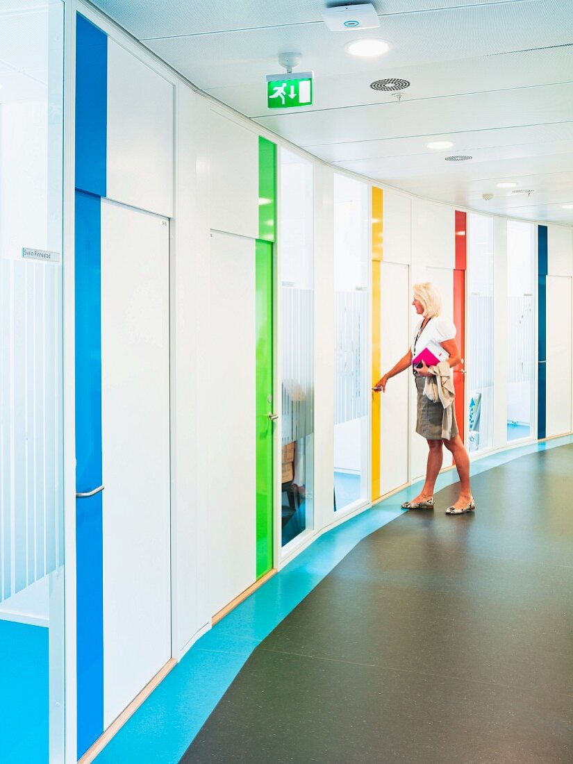 Gebogene Wand mit verschiedenen Farbakzenten im Flur einer zeitgenössischen Büroarchitektur