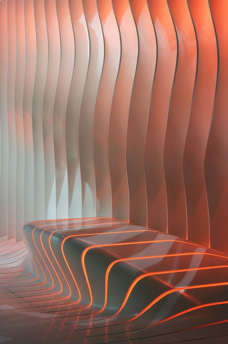 Schlitze in amorpher Wand mit integrierter Bank und farbigem Licht hinterleuchtet