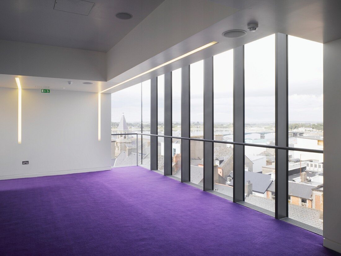 Leerer Raum mit violettem Teppich in zeitgenössischer Architektur mit Stahlglasfassade