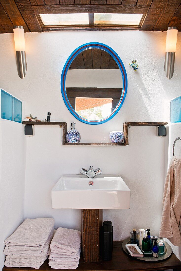 Badezimmer mit rustikalem Waschtisch und ovalem Spiegel