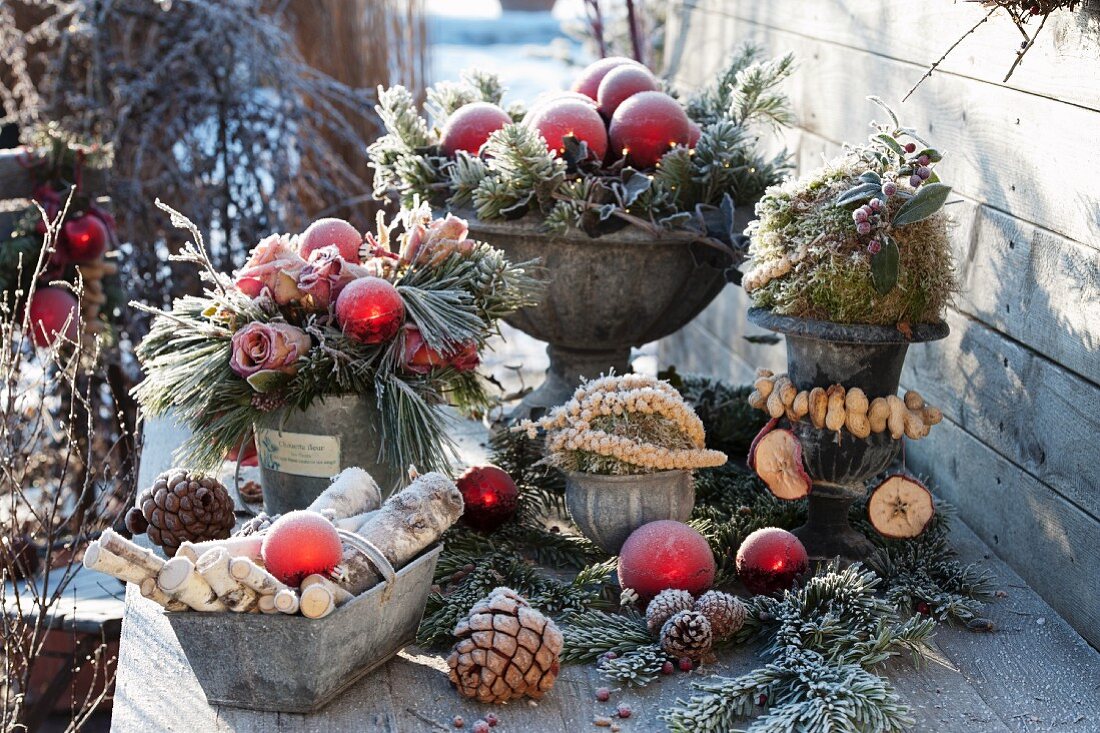 Weihnachtliches Terrassen-Arrangement mit gefrorenen Rosen, Zweigen und Kieferzapfen