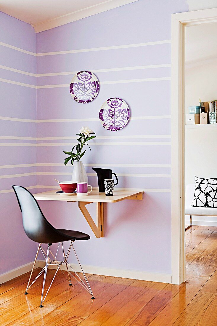 Kleine lilafarbene Essecke mit einfachem Klapptisch und schwarzem Designerstuhl