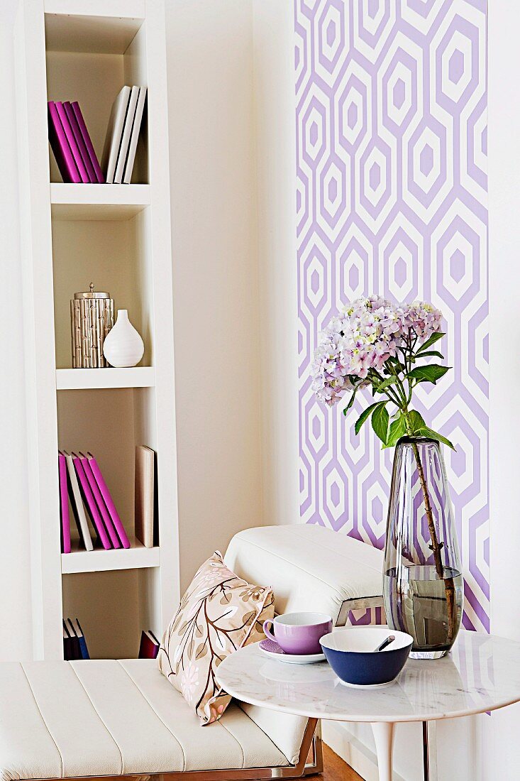 Zimmerecke in Violett, Lila und Weiß mit hohem Bücherregal und gemusterter Wandtapete