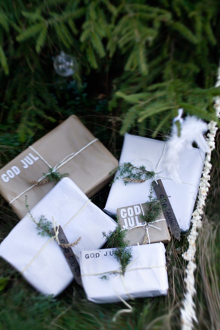 Simply wrapped gifts labelled with Swedish Christmas greetings under fir tree outside