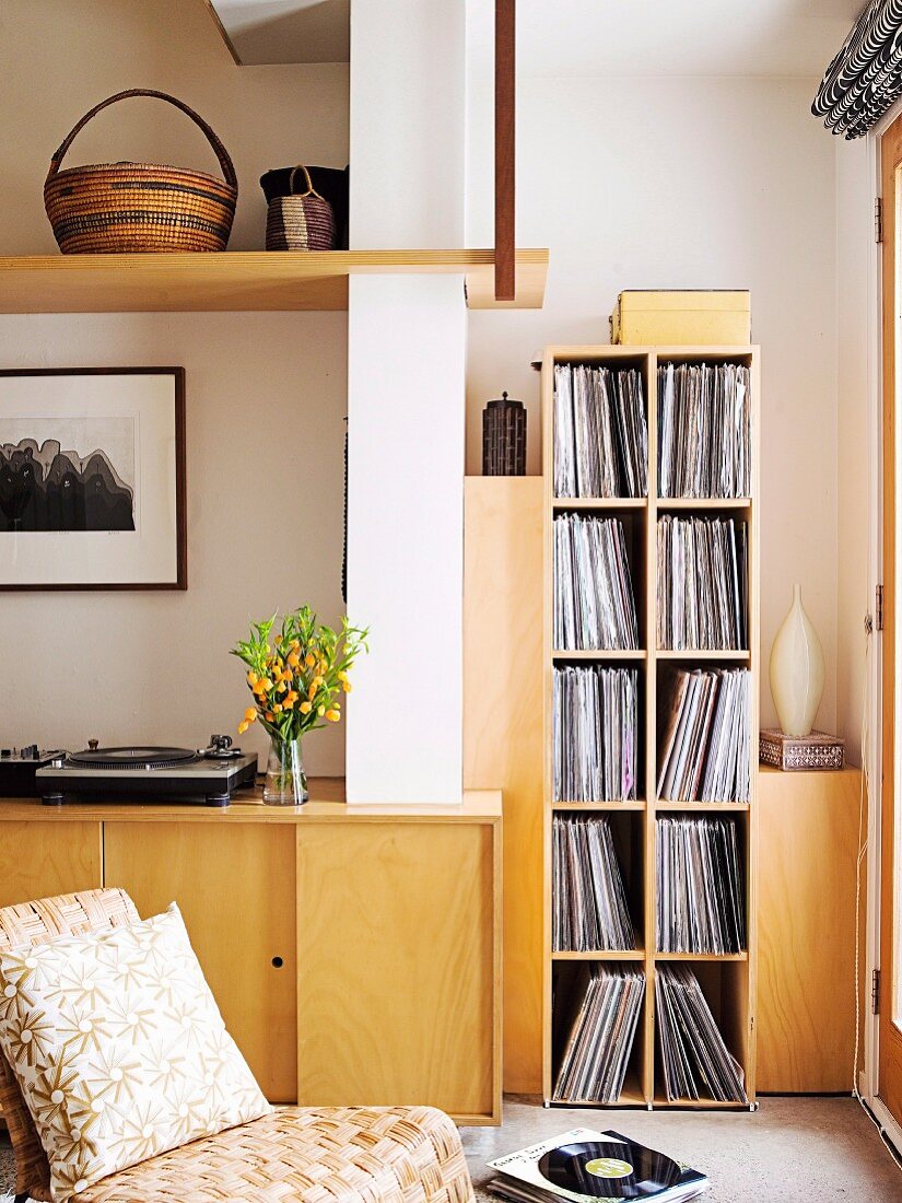 Retro chair in front of fitted sideboard and record collection on modern shelving in corner of living room
