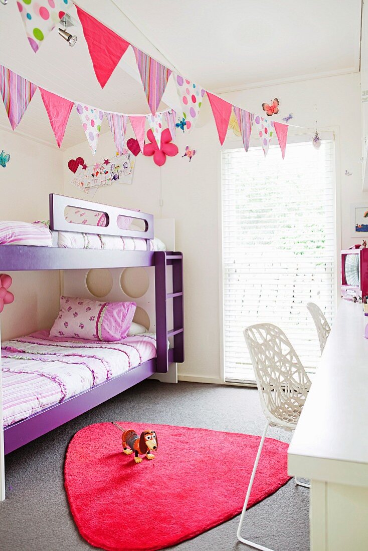 Fröhliches Kinderzimmer mit Wimpeln und vielen Farbakzenten in Lila und Pink