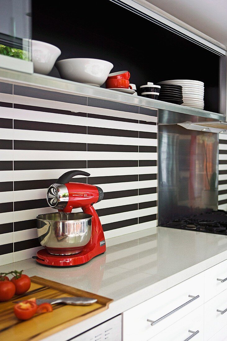 Detail of modern kitchen counter with black and white striped rear wall and wall units