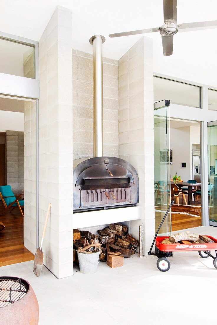 Outdoor stove on veranda and open glass door with view into interior