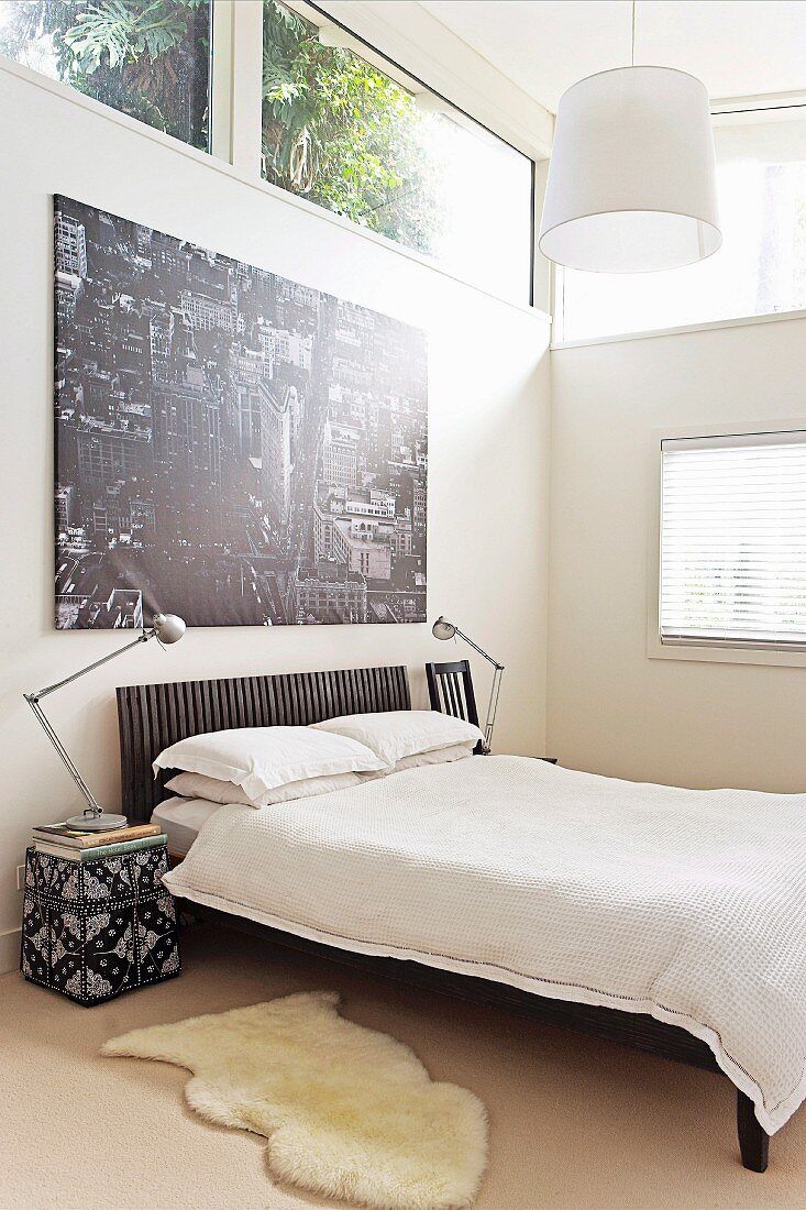 Black and white poster of city above French bed in bedroom with transom windows