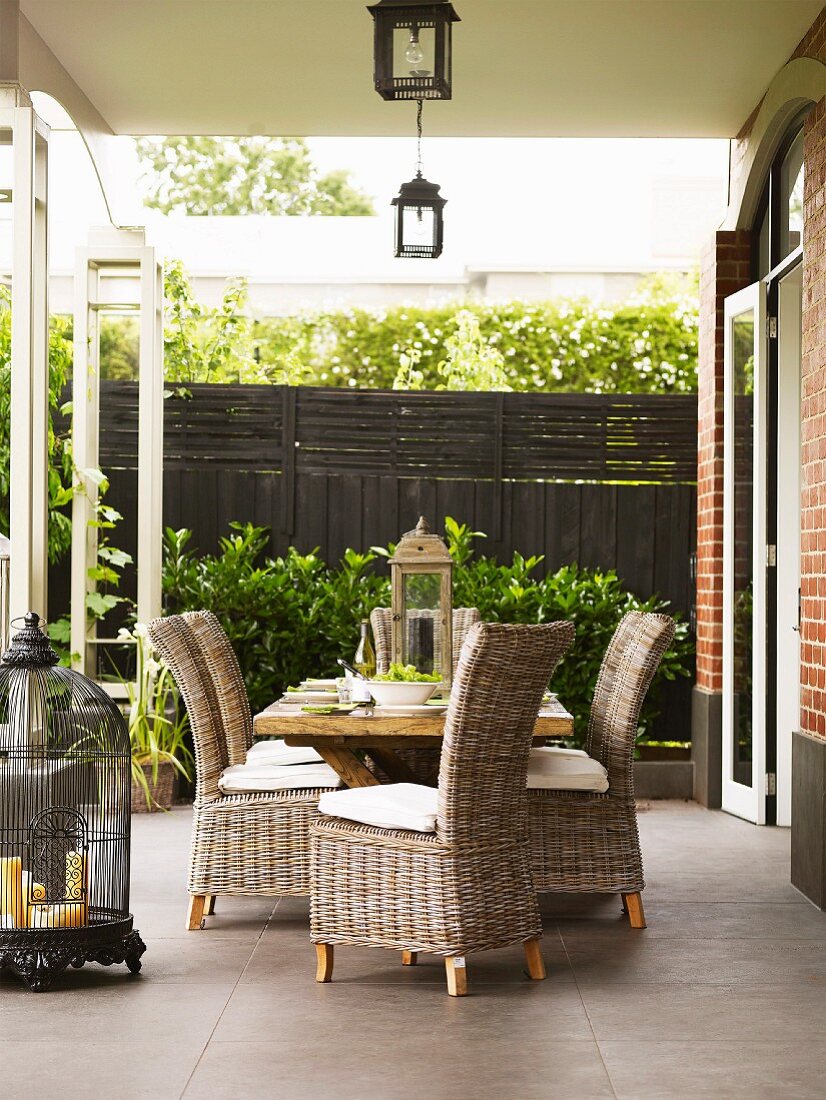 Wooden table and wicker chairs on terrace with antiquated decorative elements