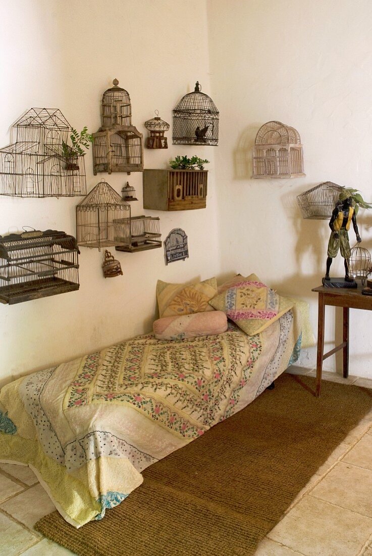 Vintage birdcages mounted on wall above couch in corner of simple room