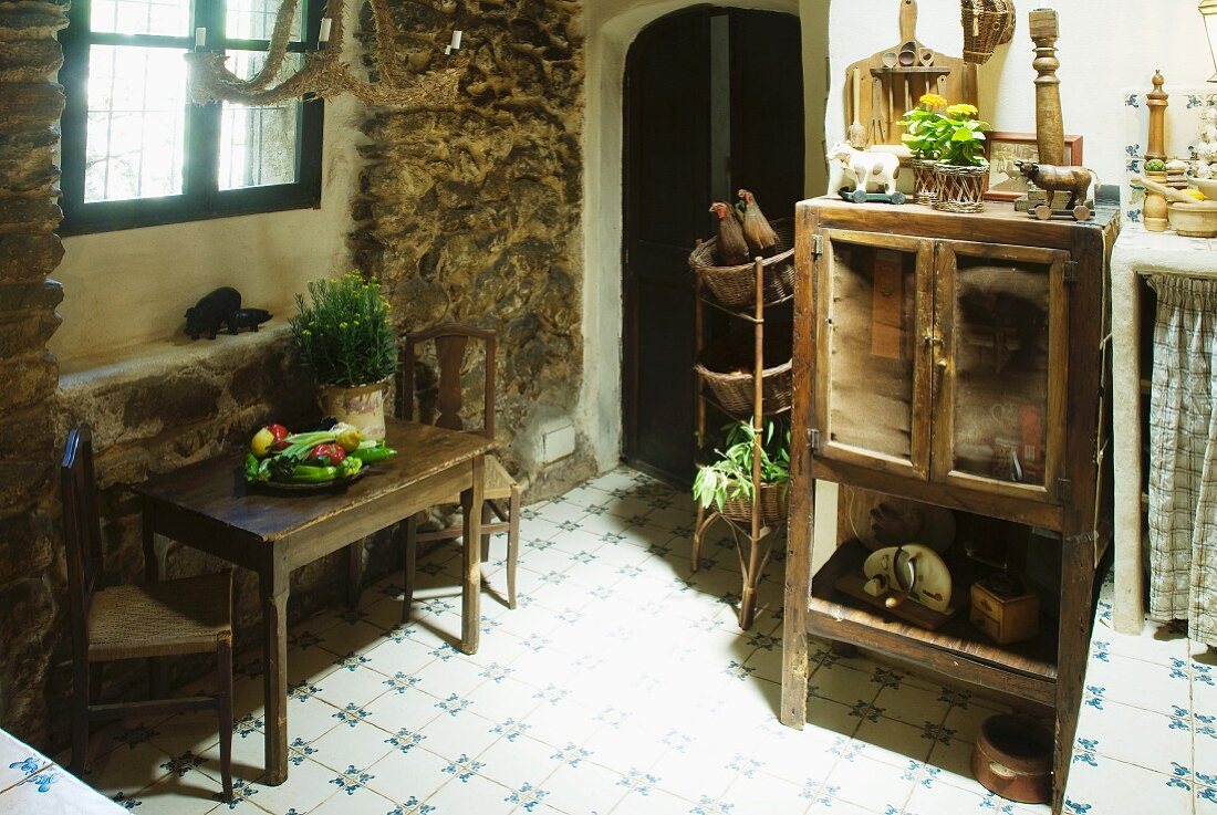 Schlichter Küchentisch mit Stühlen am Fenster und alter Küchenschrank im Esszimmer eines Rustikos