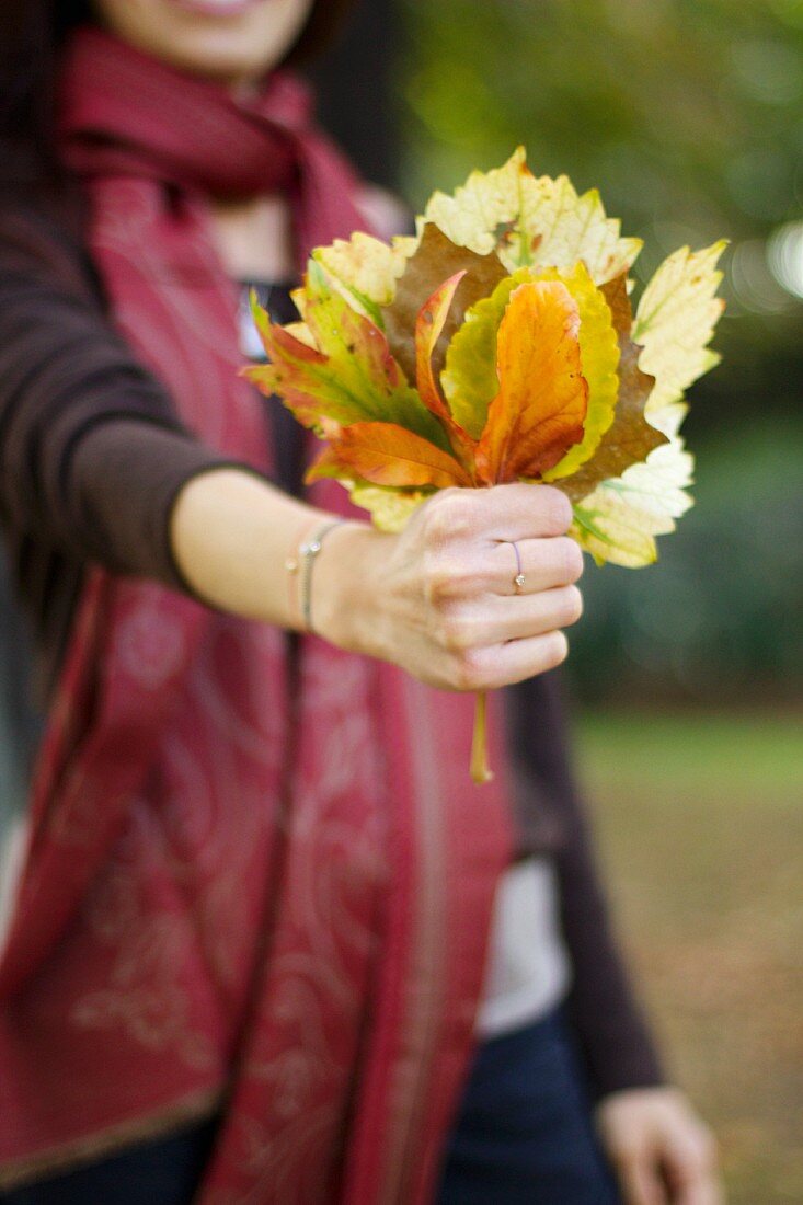 Junge Frau zeigt gesammelte Herbstblätter