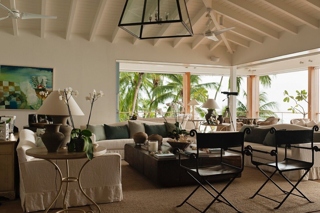 A large living area with a view of palm trees under a sloping roof