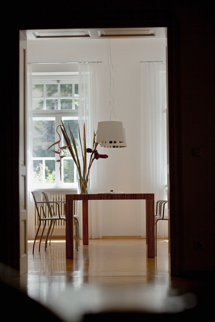 Blick durch Türöffnung auf modernen Esstisch und Designer Hängeleuchten in klassischem Ambiente