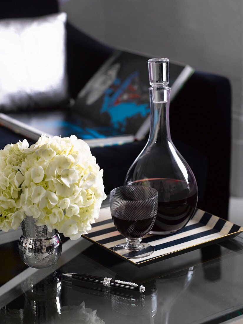 Red wine and vase of hydrangeas on side table in living room