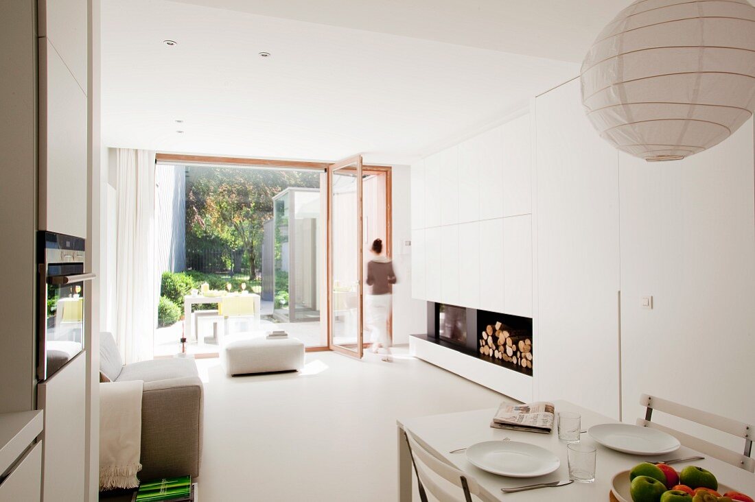 Gedeckter Esstisch in Designer Wohnzimmer mit Blick durch raumhohes Fenster auf Terrasse