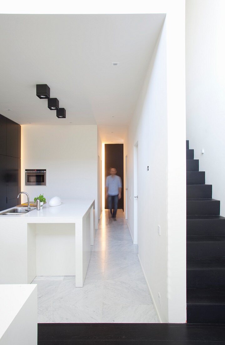 Long corridor between stairwell and kitchen in minimalist, open-plan interior