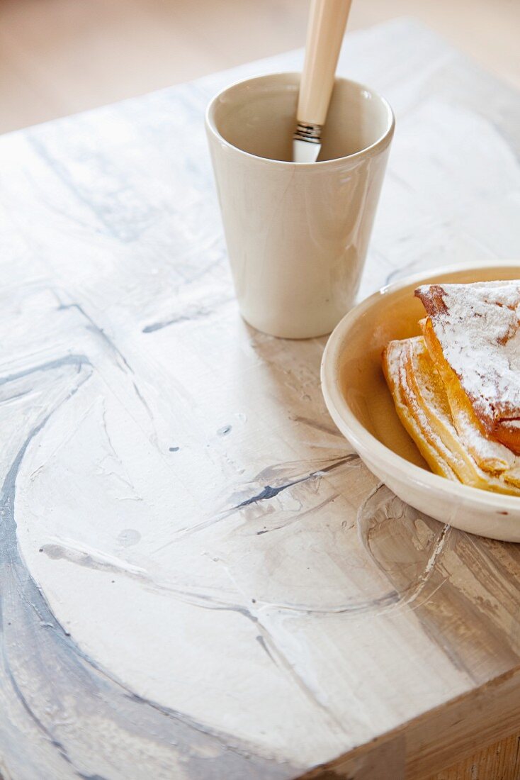 Plate of pastries and mug of tea on painted coffee table