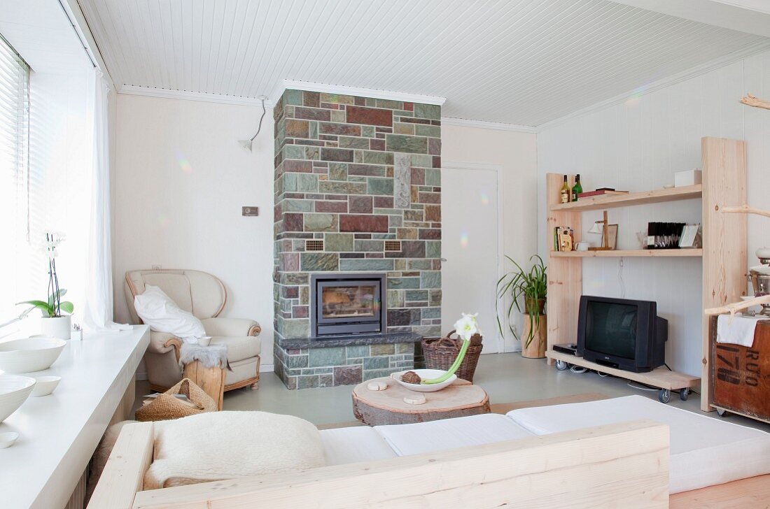 Interior with pale, simple furniture and stone-clad chimney breast