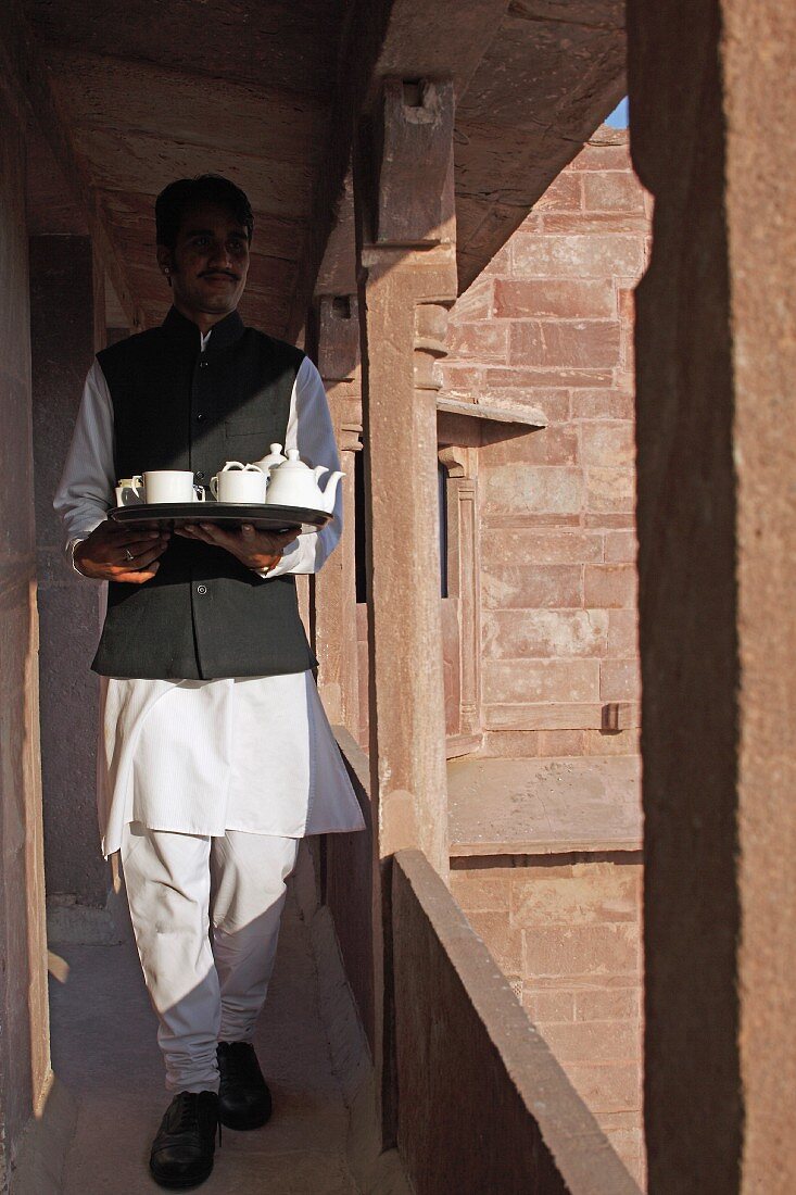 Indischer Kellner serviert Tee im Hotel Raas Haveli, Jodhpur, Indien