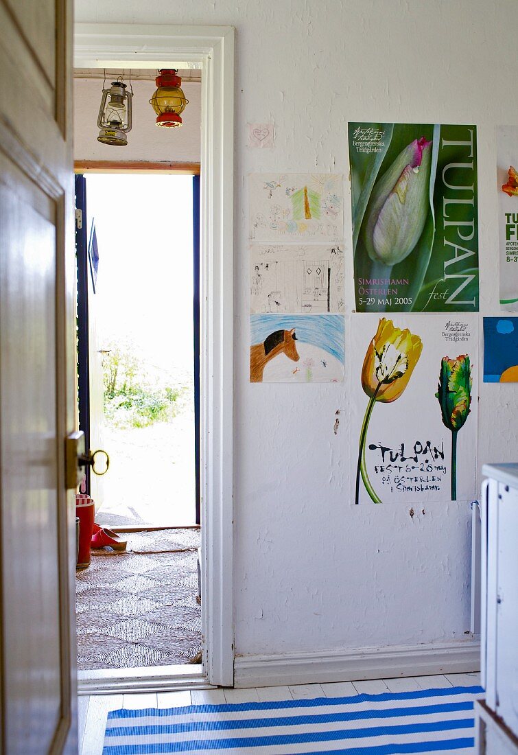 Blick durch Tür in schlichte Küche mit Postern an Wand neben offenem Durchgang und Blick ins Freie