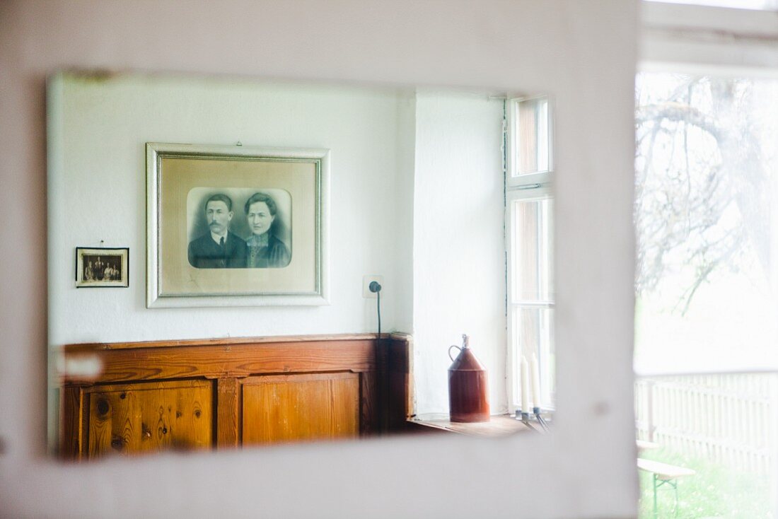 Old, framed photos hanging above wood panelling in farmhouse