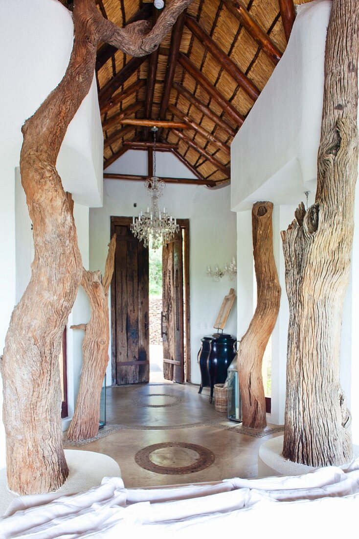 Rustikale Holzstützen in luftiger Eingangshalle mit hoher Holzbalkendecke