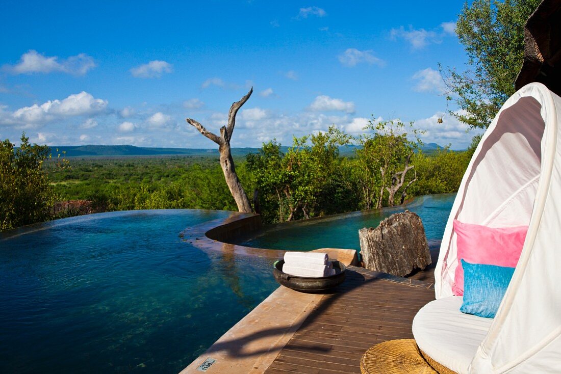 weiße Liegeinsel auf Holzdeck vor unendlich weitem Himmel und blauem Infinitypool