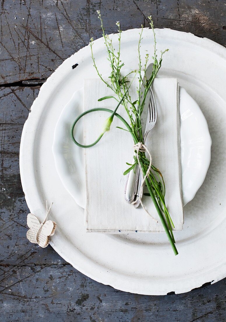 Cutlery and sprigs of herbs tied together as plate decoration