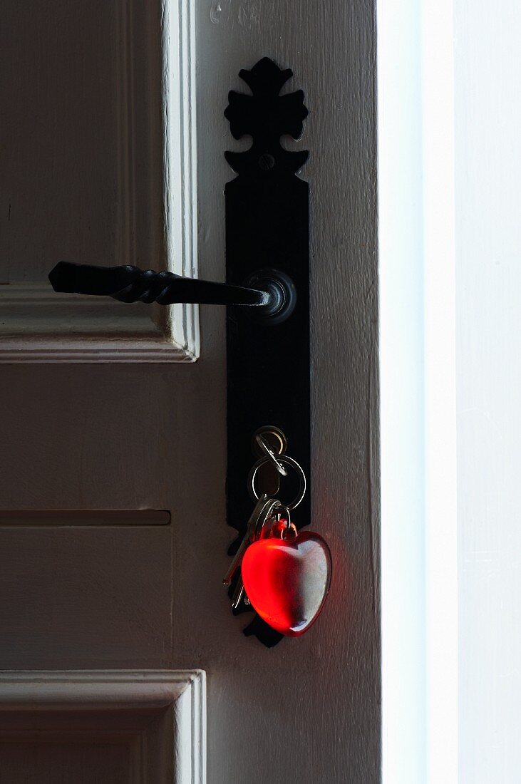 Offene alte Haustür mit Schlüsselbund und Schlüsselanhänger in Herzform